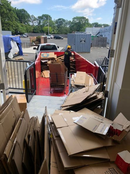 Picture of a junk removal service in Long Island that is in the process of a store clean out. You can see in the picture that they are loading in a lot of cardboard boxes in their trailer to haul it away. 